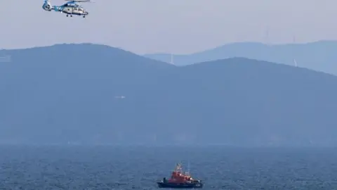 A Hellenic coastguard boat patrols the Greek waters as a helicopter flies overhead.