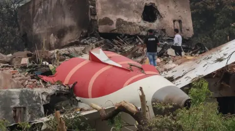 Image shows two officials inspecting the site of an airplane crash near Sardar Vallabhbhai Patel International Airport in Ahmedabad, Gujarat, western India