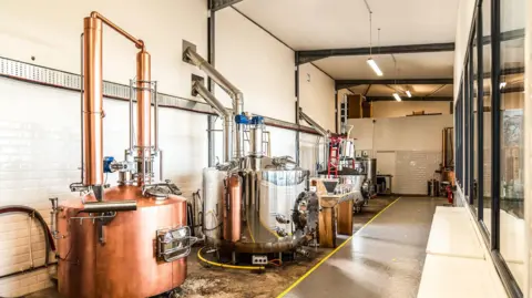 Crafty Distillery A series of stills in a distillery in different gleaming metals used for the production of gin, whisky and other spirits