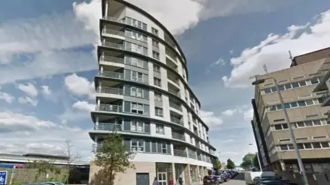 Google Exterior shot of Eastgate House, a nine-storey grey and white tower block in Woking 