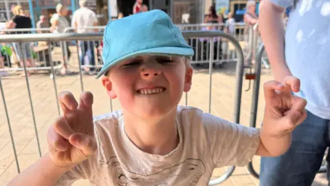 BBC / Sarah-May Buccieri Samuel, a young boy, is looking at the camera and doing a dinosaur impression