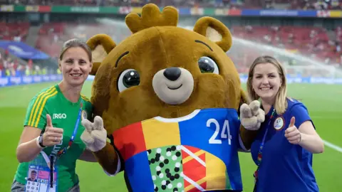 PA Media Albärt with two volunteers on the pitch