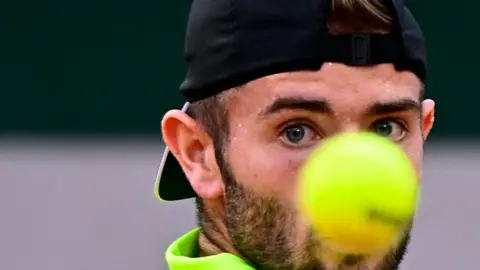 Jacob Fearnley's face partially obscured by a tennis ball