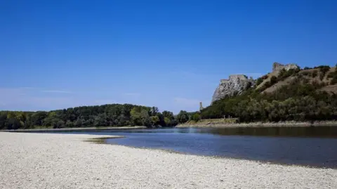 Reuters A sandbank is exposed in the low water of the Danube River during a heatwave near Hainburg an der Donau, Austria in August 2026.