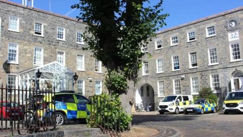 Guernsey Police building with several police cars and vans outside.