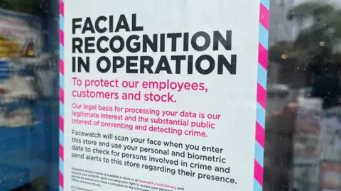 Poster sign on a shop window saying "Facial recognition in operation to protect our employees, customers and stock. Our legal basis for processing your data is our legitimate interest and the substantial public interest of preventing and detecting crime."