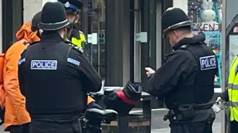 BBC Three police officers talking to a food delivery rider outside the Highcross shopping centre