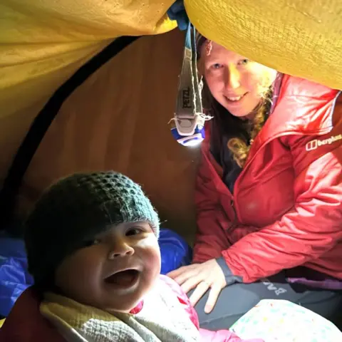 Morag Skelton Hamish and Morgan in a yellow tent. He is wearing a green hat and she is wearing a red jacket.
