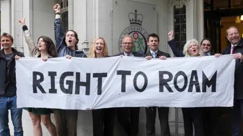 A number of people celebrating behind a banner that says "right to roam"