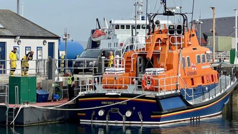 A police officer stands by Kirkwall RNLI lifeboat which is berthed in Kirkwall harbour.