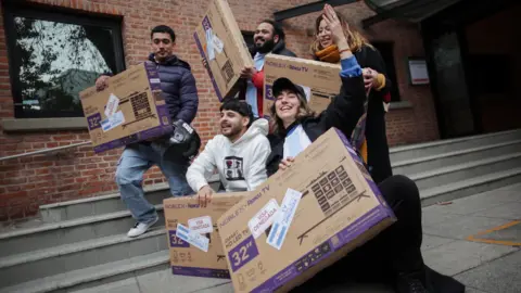 People pose with television sets they received for free after showing their U.S. visa denials during a promotion by television manufacturer Noblex for people unable to travel to the World Cup due to visa rejections.