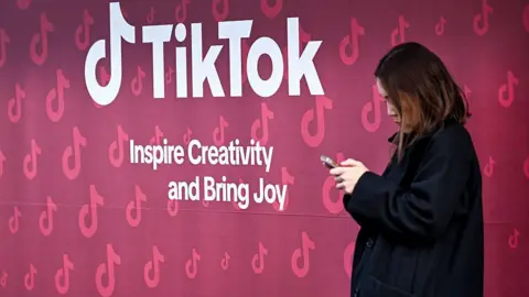 A woman uses her phone in front of Tiktok's booth during the World Economic Forum (WEF) annual meeting in Davos