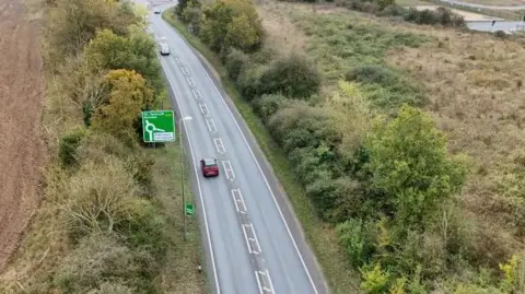 Shaun Whitmore/BBC An aerial of the A47 in Norfolk. A green road sign points straight ahead of Great Yarmouth and Norwich whereas to the right it says Mattishall and Honingham. 