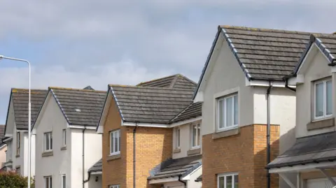 Row of houses with cream walls and orange bricks.