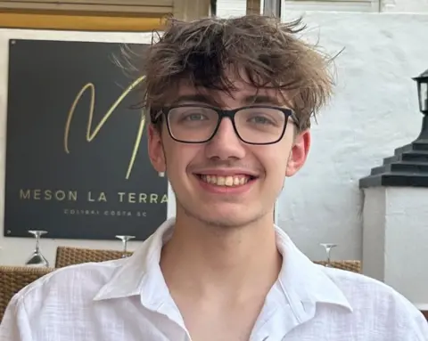 Kieran Miller A man in a white shirt and dark glasses smiles
