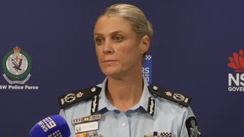 A female police officer stands behind a microphone at a press conference