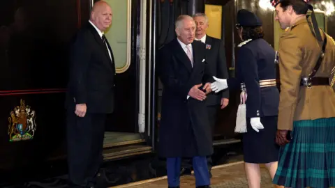 Reuters King Charles III is exiting the train and about to shake hands with a uniformed lady on the platform
