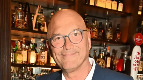 Getty Images Gregg Wallace wearing a blue suit and white shirt with a bar in the background