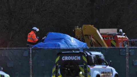 NEMM A photograph of recovery vehicles and a worker in hi-vis at the scene