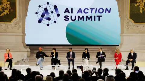 Speakers sitting on stage with a huge screen behind them that says "AI Action Summit" and the event's logo