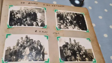 A photo album with black and white pictures of sailors on a ship