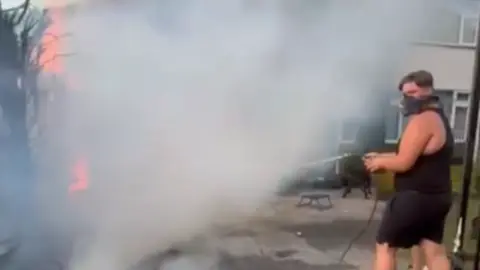 Sealius Boy in tank top puts out flames.