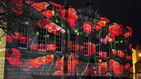 Stafford's Shire Hall building, with a light display depicting poppies illuminated on the front of the building.