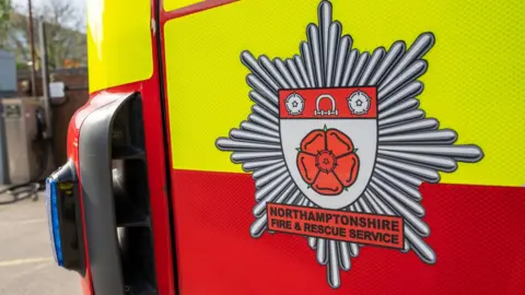 The badge of Northamptonshire Fire and Rescue shown on the side of a fire truck.