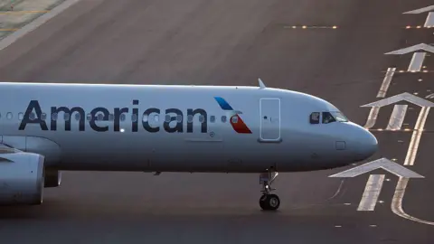 The front of an air plane with the American logo on a runway. 