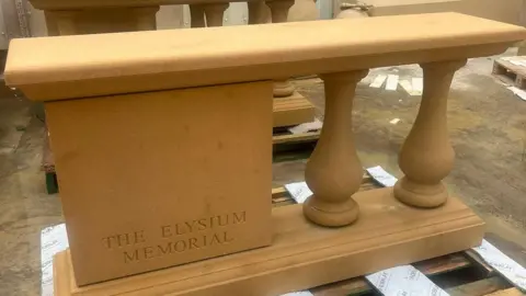An image of the Elysium Memorial showing a stone structure engraved with the foundations name. On the right of the image are two columns supporting the structure.