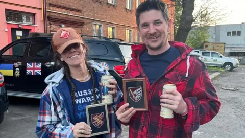 Ed Chalmers Katie and Ed standing in front of the vehicle