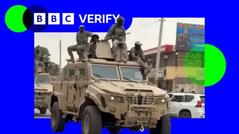 RSF fighters ride on an armoured truck in the city of Nyala. One of the fighters is carrying an assault rifle. All are dressed in military fatigues.