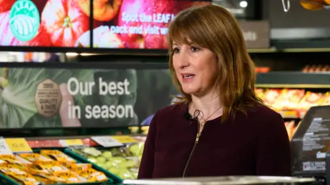 Pa Media Rachel Reeves standing in front of the fruit aisle in a Tesco supermarket wearing a top
