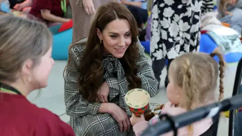 Pa la princesa de Gales sonriendo con una pequeña niña blanca con cabello rubio y coletas