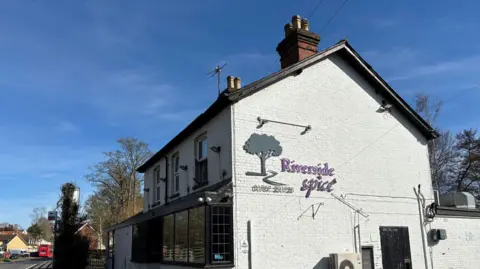 A white building that reads 'Riverside Spice' and a phone number on the side 