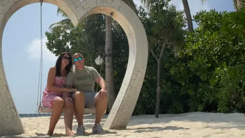 Natalie Chetkowski A man and a woman sat on a swing inside a heart-shaped structure on the beach