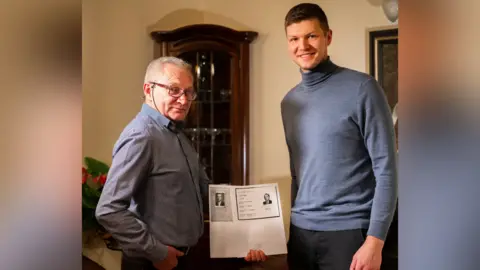 Meerkat PR First picture of Krzysztof Sadowski - Domanski’s nephew with Polish probate researcher, Benjamin Ratz of GEN SPZOO - he’s the younger blonde man, Ben Ratz. The older man is Krzysztof, with black-rimmed glasses and wearing a grey shirt. Ratz has a light blue turtle neck on.