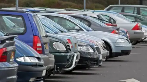 Getty Images Image shows a row of cars parked in a car-park