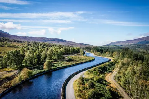 An open water channel, which looks like a canal, carries water from a dam at the Dunalastair Reservoir