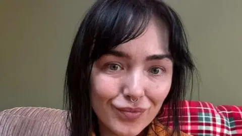 A woman with brown hair stares at the camera 