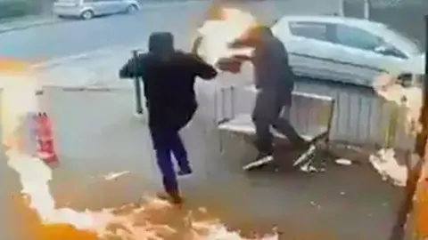 Two men who tried to set fire to a shop are hopping around outside with flames around them