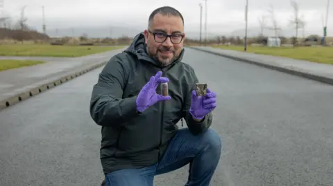 Swansea University Dr Jose Norambuena-Contreras pictured on the road with his substance in hand. 