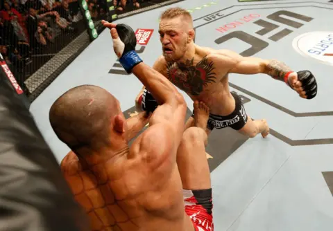 Getty Images Conor McGregor, in trunks, lifts his left fist to prepare to punch Diego Brandao, also in trunks, during a UFC fight