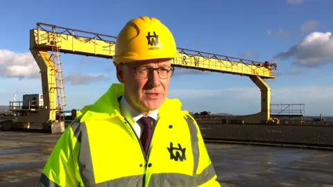 John Swinney in a yellow hard hat and high vis yellow jacket