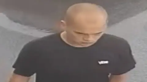 CCTV image released by police of a man with a shaved head and black T'shirt in a street