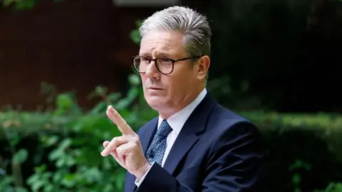 Sir Keir Starmer, the UK's prime minister, delivering a speech in the Rose Garden at Downing Street in London, where a blue-suit, patterned tie and glasses