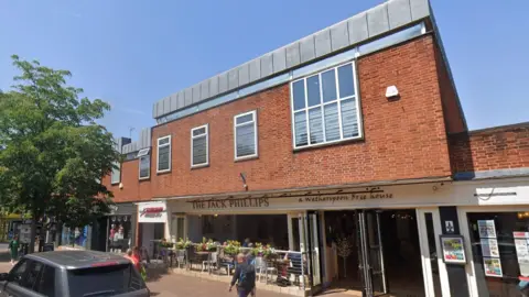The Jack Phillips pub on the ground floor of a two-storey 1960s brick building.