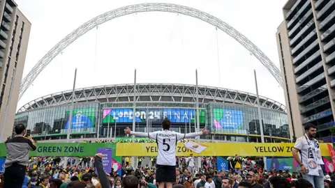 Reuters Exterior of Wembley Stadium showing the white arch and signs saying London 2024 final with fans wearing football kits gathering for the 2024 European Champions League final 