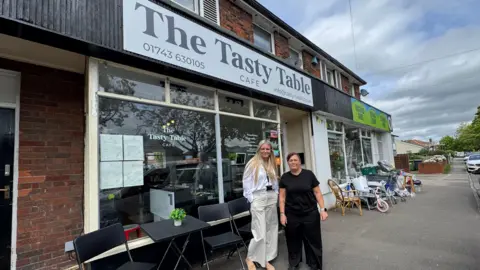 Donna Jones Donna Jones and cafe employee Kerry Rowe standing outside the cafe on Whitchurch Road, they are standing next to eachother and both are smiling into the camera.