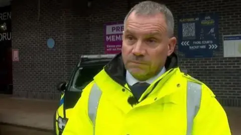 Adrian Leisk wearing a yellow coat over a white shirt and black tie